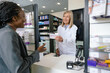 © zinkevych - African american young woman paying at the cashier desk at the pharmacy