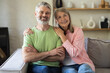 © zinkevych - Smiling senior couple posing for portrait while sitting on sofa