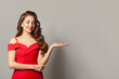 © artmim - Attractive model woman holding empty open palm hand and smiling on white background