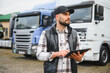 © Serhii - Truck driver using digital tablet managing fleet logistics