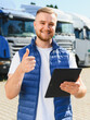 © Serhii - Truck driver giving thumbs up holding tablet