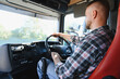 © Serhii - Truck driver steering vehicle on road trip