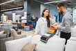 © Serhii - Woman buying sofa with sales consultant comparing fabric samples
