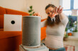 © wifesun - Woman performing essential household maintenance by taking out a visibly dusty filter from an air purifier, promoting awareness of indoor air quality, health, and allergy prevention