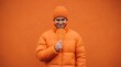 © Yauhen - Portrait of a playful man in orange outfit holding a large swirl lollipop against an orange wall. The scene embodies a kidult lifestyle and vibrant monochromatic aesthetics for fun ads.