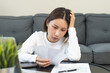 © KMPZZZ - Debt and financial concept, stressed asian young woman have a headache while female calculate expenses, income and expenses, looking bills of credit card for payment or payday on table at home office.