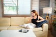 © Stella 16 - woman wears black tank shirt hold drink clear fresh pure still water from transparent glass sit on yellow couch stay at home flat rest relax spend free spare time in living room indoor