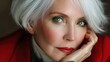 © Newleks - Elegant senior woman with short white hair portraying confidence and unique style, wearing a bold red jacket, featuring vibrant green eye makeup and red lipstick, looking towards the camera
