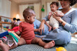 © Jovo Jovanovic/Stocksy - Mother and babies playing with toys on the floor.