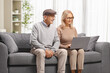 © Ljupco Smokovski - Mature man and woman sitting on a sofa and working on a laptop computer
