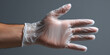 © Artificial South - A hand wearing a clear plastic glove against a solid gray backdrop. The glove is stretched out, revealing the fingers inside