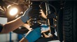 © Masaji - Close-up of mechanic's gloved hands carefully adjusting a car's shock absorber during a vehicle repair.