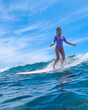 © truphotovideo - Young Woman Demonstrating Surf Technique On Gentle Swell, Confident Posture And Instructional Vibe With Bright