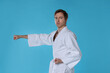© New Africa - Man in uniform practicing karate on light blue background