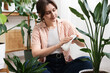 © New Africa - Woman wiping beautiful houseplant leaf at home