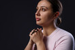© New Africa - Woman with cross praying on black background, space for text