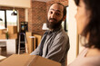 © DC Studio - Bearded white man with girlfriend arriving at recently purchased home, holding cardboard boxes and stepping into new living space. Caucasian couple moving in with packed belongings.