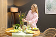 © New Africa - Woman arranging beautiful flowers at table indoors. Easter celebration
