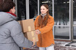 © New Africa - Woman receiving parcels from delivery man outdoors