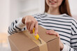 © New Africa - Woman opening parcel with knife at home, closeup