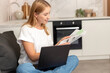 © brizmaker - Woman using a laptop at home to manage online shopping and booking tasks