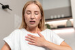 © brizmaker - Mature woman experiences chest discomfort while sitting in living room at home
