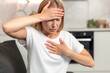 © brizmaker - Woman experiencing chest pain and anxiety at home due to health issues
