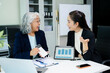 © Nuttapong punna - Asian business women discussing finance data using tablet and calculator in a modern office, showing teamwork, mentorship, analysis, and professional corporate collaboration.
