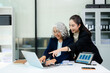 © Nuttapong punna - Asian business women discussing finance data using tablet and calculator in a modern office, showing teamwork, mentorship, analysis, and professional corporate collaboration.