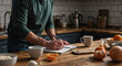 © Vyatcheslav - Man writing in a notebook on a wooden kitchen counter. Person planning a healthy meal or journaling in the morning. Healthy lifestyle and productivity concept