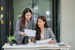 © aekachai - Two Asian businesswomen working with documents in an office.
