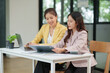 © aekachai - Two Asian businesswomen working with documents in an office.