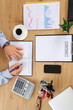 © Pixel-Shot - Young businessman with mobile phone, documents and cup of coffee writing in notebook on table at office, top view