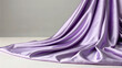 © Hanna - Silk fabric in lavender color draped on a surface, showing smooth texture and gentle folds in soft lighting