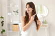 © Pixel-Shot - Beautiful young happy woman combing her hair in bathroom at home