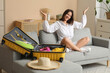 © Pixel-Shot - Happy young woman packing suitcase for travel on sofa in living room