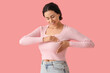 © Pixel-Shot - Young African-American woman checking her breast on pink background. Cancer awareness concept