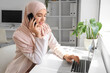 © Pixel-Shot - Beautiful Muslim businesswoman with laptop talking by mobile phone at desk in office