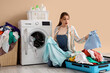 © Pixel-Shot - Surprised young woman with pile of dirty laundry in suitcase near washing machine on beige background