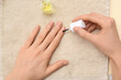 © Pixel-Shot - Female hands applying cuticle oil with brush on beige towel