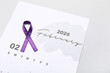 © Pixel-Shot - Purple ribbon and paper calendar on grey background. Cancer awareness concept