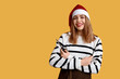 © Pixel-Shot - Young female hairdresser in Santa hat with comb and scissors on yellow background