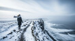 © pufanya - Woman walking on snowy clifftop path. Cold winter landscape with windblown scarf. Grey ocean view
