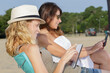 © auremar - cheerful young women using a tablet on the beach