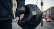 © Qii Stock - Close-up of Motorcyclist in Leather Gloves Holding Black Matte Helmet