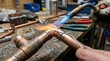 © IbragimovN - Close-up of copper pipe welding and tools in workshop setting