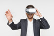© InsideCreativeHouse - Young business man in formal suit using VR glasses experience virtual reality via VR headset and touching something with hands, modern technology. Isolated on white background studio portrait.