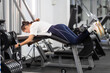© KONSTANTIN SHISHKIN - Woman exercising hamstrings on leg curl machine in a gym