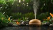 © Imamstudio - A modern orange essential oil diffuser emitting a fine mist surrounded by smooth stones and lush green foliage
