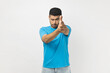 © khosrork - Portrait of strict bossy attractive unshaven man wearing blue T- shirt standing showing finger gum to camera, shooting to you, wants to kill somebody. Indoor studio shot isolated on gray background.